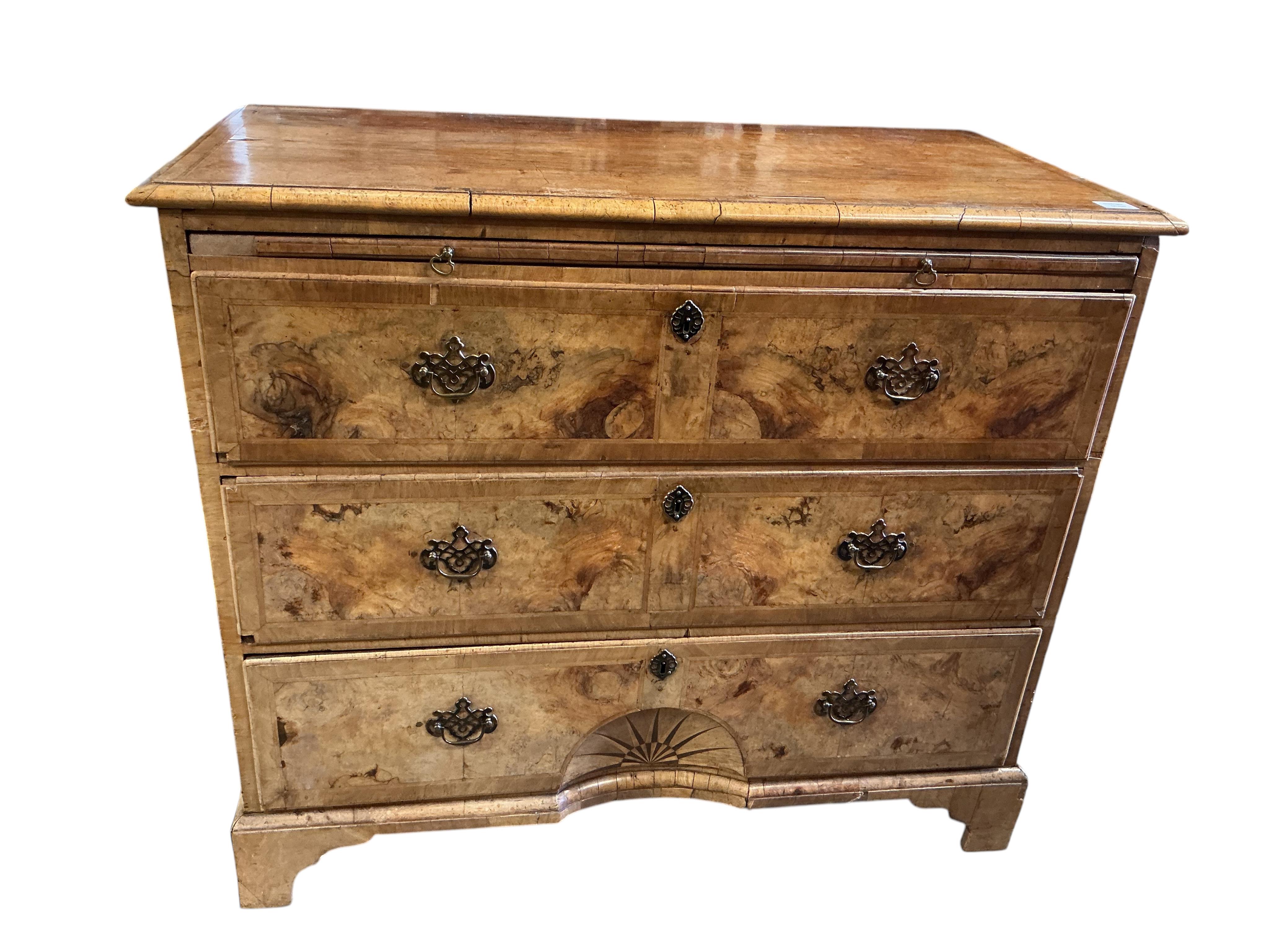 A mid 18th century feather banded walnut concave starburst walnut chest of three drawers, with brushing slide, width 108cm, depth 54cm, height 92cm